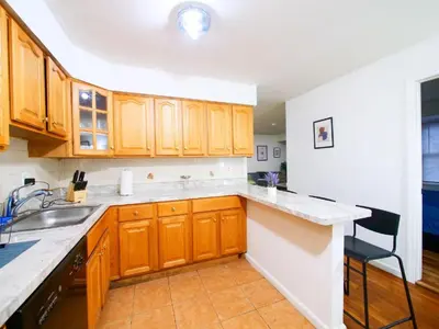 a kitchen with wooden cabinets and a sink at Bright Private Room with Shared Bathroom near NYC in Jersey City