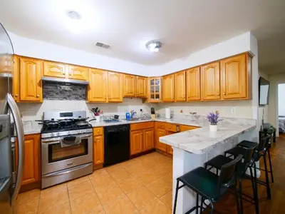 a kitchen with wooden cabinets and a stove top oven at Charming Private Room in a Friendly Home mins to NYC in Jersey City