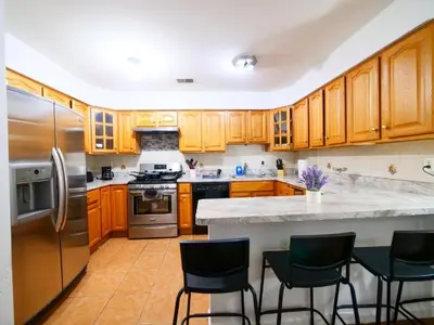 a kitchen with wooden cabinets and stainless steel appliances at Charming Private Room in a Friendly Home mins to NYC in Jersey City