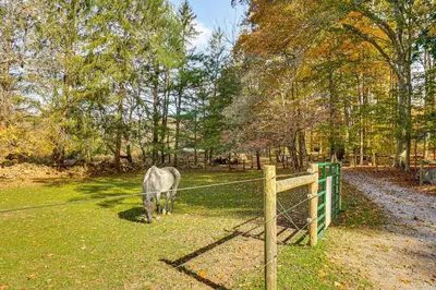 a horse grazing in a field next to a fence at Serene Getaway with Trail Access in Chester Springs in Chester Springs