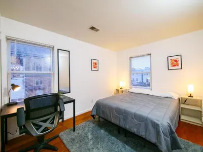 a bedroom with a bed and a desk and two windows at Private Bedroom with Shared Amenities mins to NYC in Jersey City