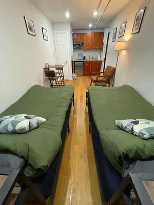 two beds in a small room with a kitchen at Union Square Studio with Kitchen -Shared Bathroom in New York