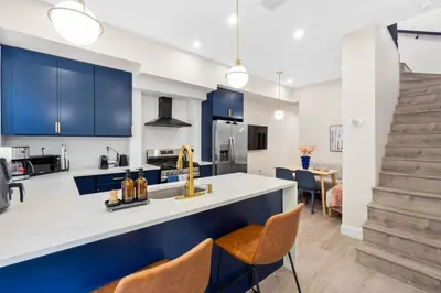 a kitchen with blue cabinets and a counter with chairs at Elegant Home w Patio | In-Unit Laundry Near NYC in Jersey City