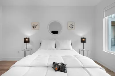 a white bedroom with a white bed with a purse on it at Luxury 1BR Getaway - Modern Stylish & Great Area in Philadelphia