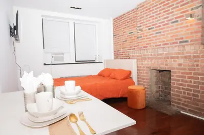 a living room with a table and a brick wall at West Village Escape - Steps from Subway Cafes in New York