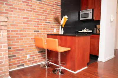 a bar with an orange stool next to a brick wall at West Village Escape - Steps from Subway Cafes in New York