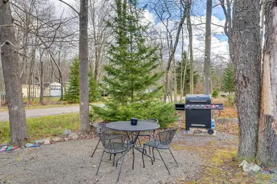 a picnic table with chairs and a grill in the woods at Game Room, Hot Tub and Fire Pit Pocono Lake Escape! in Pocono Lake