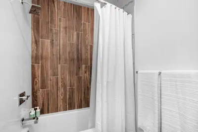 a bathroom with a shower with a wooden wall at Premium 1BR - Workstation Pool Balcony in Philadelphia