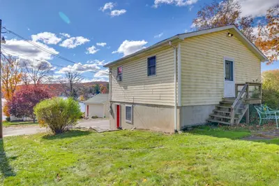 a small yellow house with a staircase in a yard at Hike, Ski and Golf Water-View Lake Winola Retreat! in Factoryville