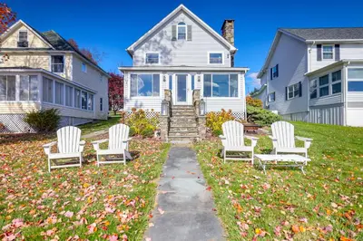 four white chairs in a yard in front of a house at Scenic Waterfront Home with Dock on Lake Winola! in Factoryville