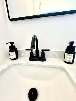 a bathroom sink with two bottles of soap on it at Newly Built Lake House Near NYC EWR MetLife AD Mall in Passaic