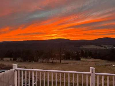 a sunset over a field with a white fence at Rest in Wellsville