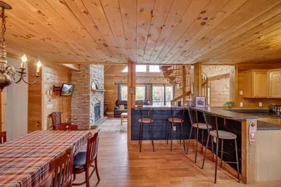 a kitchen with wooden ceilings and a bar with stools at Secluded Retreat near Ski Resorts, Hot Tub, BBQ in Blakeslee