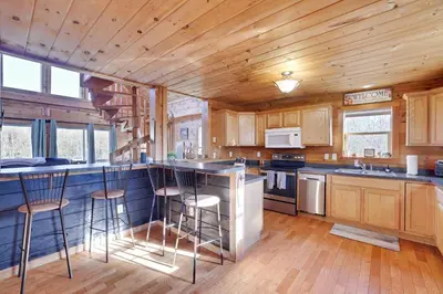 a kitchen with wooden cabinets and a counter with stools at Secluded Retreat near Ski Resorts, Hot Tub, BBQ in Blakeslee