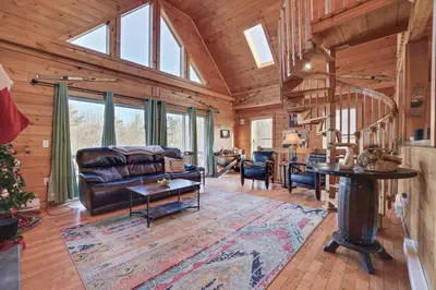 a living room with a leather couch and a table at Secluded Retreat near Ski Resorts, Hot Tub, BBQ in Blakeslee