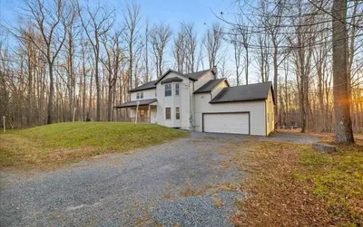 a white house with a garage on top of a driveway at Lake Area 6BR Pet friendly home in Poconos - Your Pocono Retreat in Thornhurst