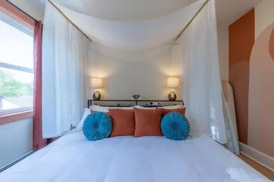 a bedroom with a white bed with orange and blue pillows at Zen Den With King Bed and Very Close to Airport in Newark