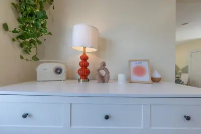 a white dresser with a lamp and a clock on it at Zen Den With King Bed and Very Close to Airport in Newark