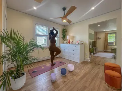 a woman doing a yoga pose in a living room at Zen Den With King Bed and Very Close to Airport in Newark