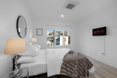 a white bedroom with a bed and a mirror at Modern 1BR Escape - Balcony Gym Wi-Fi in Philadelphia