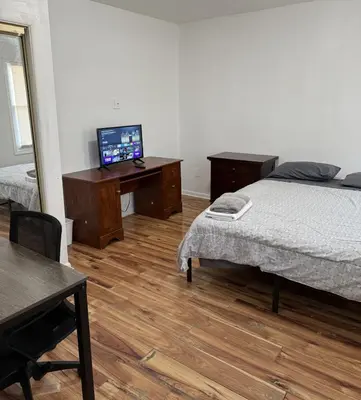 a bedroom with a bed and a desk with a television at Private house with 4 bedrooms 2 bathrooms, NYC direct bus 1 block away, MetLife Stadium FIFA World Cup 30 minutes away in Perth Amboy