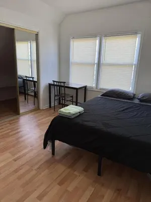 a bedroom with a bed and a table and chairs at Private house with 4 bedrooms 2 bathrooms, NYC direct bus 1 block away, MetLife Stadium FIFA World Cup 30 minutes away in Perth Amboy