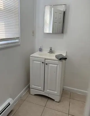 a white bathroom with a sink and a mirror at Private house with 4 bedrooms 2 bathrooms, NYC direct bus 1 block away, MetLife Stadium FIFA World Cup 30 minutes away in Perth Amboy