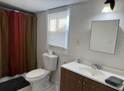 a bathroom with a toilet and a sink and a mirror at Private house with 4 bedrooms 2 bathrooms, NYC direct bus 1 block away, MetLife Stadium FIFA World Cup 30 minutes away in Perth Amboy