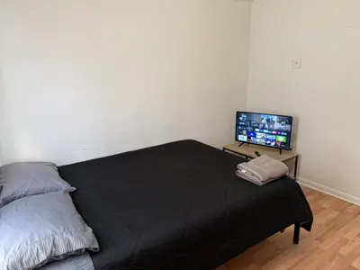 a bedroom with a bed and a flat screen tv at Private house with 4 bedrooms 2 bathrooms, NYC direct bus 1 block away, MetLife Stadium FIFA World Cup 30 minutes away in Perth Amboy
