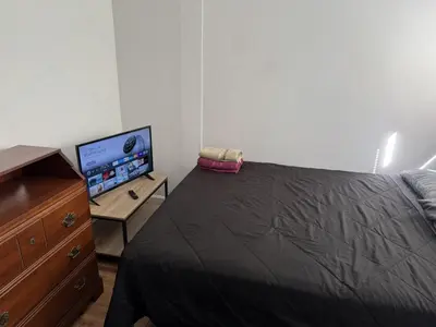 a bedroom with a bed and a dresser with a television at Private house with 4 bedrooms 2 bathrooms, NYC direct bus 1 block away, MetLife Stadium FIFA World Cup 30 minutes away in Perth Amboy