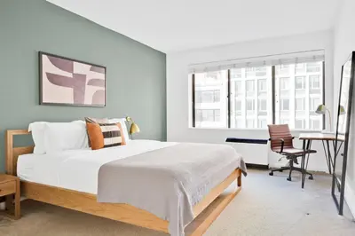 a bedroom with a large bed and a desk at Blueground Chelsea fitness center nr Madison Square Park NYC-390 in New York