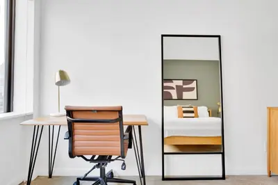 an office with a mirror next to a desk and a bed at Blueground Chelsea fitness center nr Madison Square Park NYC-390 in New York