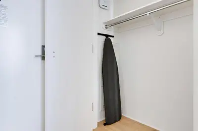 a closet with a black tie hanging on a door at Blueground Chelsea pool nr The Vessel NYC-2144 in New York