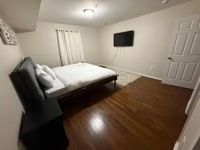 a bedroom with a bed and a flat screen tv at COZY 3 bedroom APT near EWR Downtown NYC in Newark