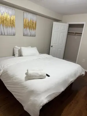 a white bed with a towel on top of it at COZY 3 bedroom APT near EWR Downtown NYC in Newark