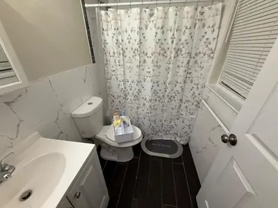a bathroom with a toilet and a shower curtain at COZY 3 bedroom APT near EWR Downtown NYC in Newark