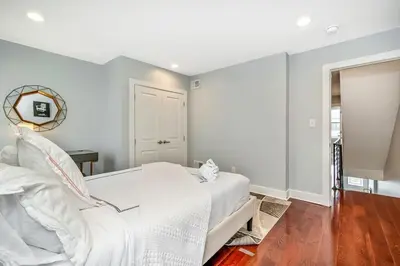 a white bedroom with a white bed and a mirror at Outstanding Home Relaxing Rooftop with Patio & Grill in Philadelphia