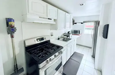 a white kitchen with a stove and a sink at Professional & Student-Friendly in Upper Darby