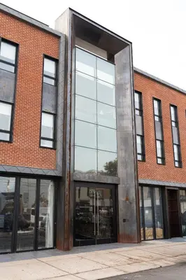 a large brick building with a large window at Sosuite at The Queen - Queen Village in Philadelphia
