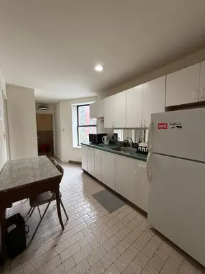 a kitchen with white cabinets and a table and a refrigerator at Hudson Yard 4 in New York