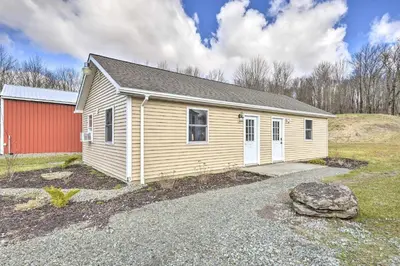 a small house with a red building in a field at Woodland Hideout near Ski Adventures in Pleasant Mount
