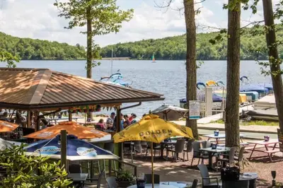 a dock with tables and umbrellas and boats on a lake at Gorgeous Chalet in the Poconos w/ Hot Tub! in Locust Lakes Village