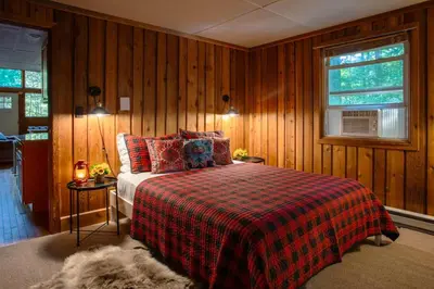 a bedroom with a bed with a plaid blanket and a window at Gorgeous Chalet in the Poconos w/ Hot Tub! in Locust Lakes Village