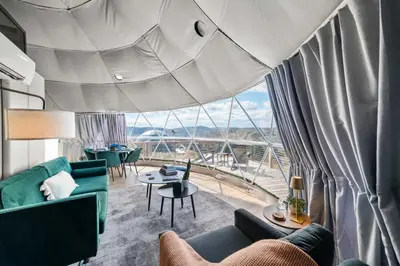a living room with a green couch and a large window at Glamping Getaway at 'The Coyote Dome' in Franklin in Franklin