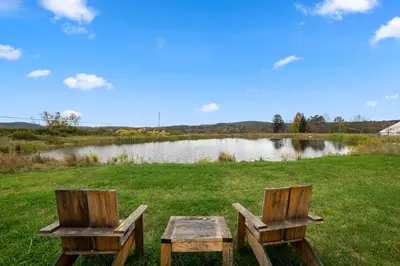 two wooden benches sitting in front of a lake at Glamping Getaway at 'The Coyote Dome' in Franklin in Franklin