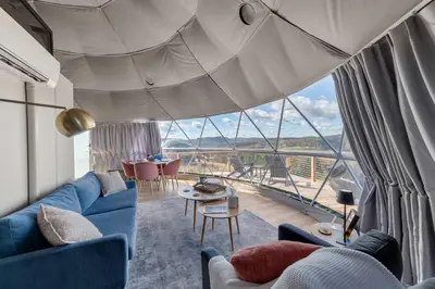 a living room with a blue couch and a large window at 'The Bear Dome' with Barrel Hot Tub in Franklin in Franklin