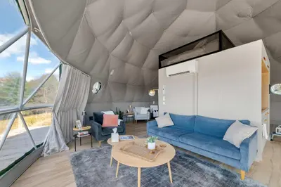 a living room with a blue couch and a table at 'The Bear Dome' with Barrel Hot Tub in Franklin in Franklin