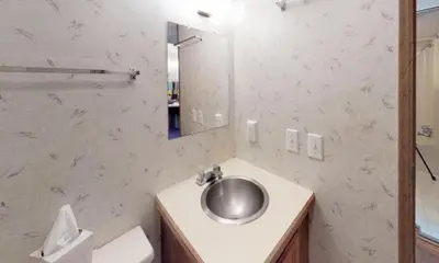 a bathroom with a sink and a toilet and a mirror at Jellystone Park PA Wilds in Mansfield