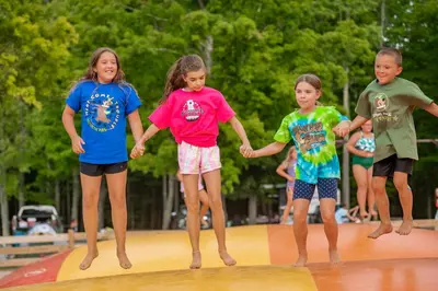 a group of children holding hands on a surfboard at Jellystone Park PA Wilds in Mansfield