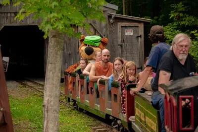 a group of people riding on a small train at Jellystone Park PA Wilds in Mansfield